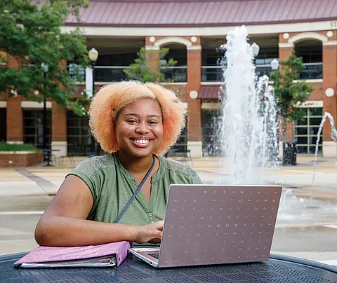Young woman with laptop and binder